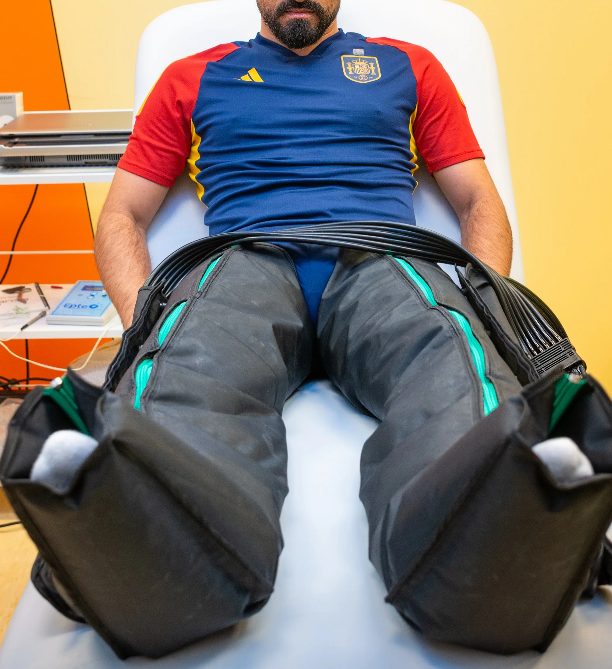 Paciente sentado en una camilla con botas de presoterapia